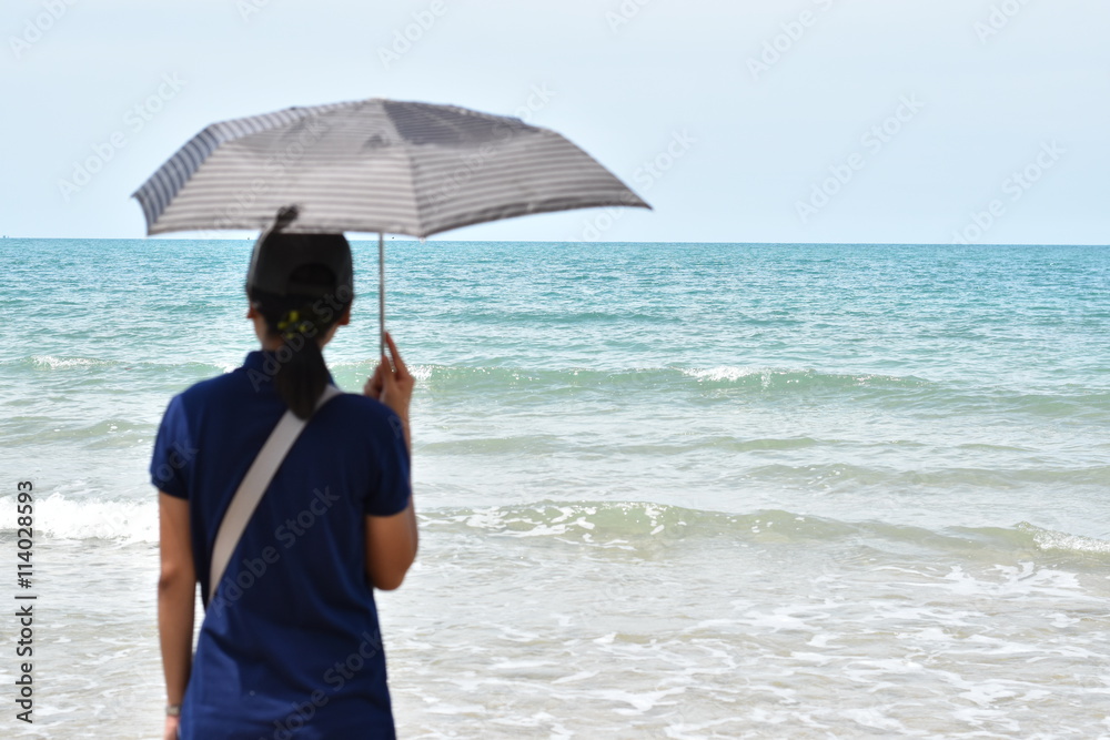 Asian woman and umbrellas. Standing on the beach, blue sky. Asian woman and umbrellas. Standing on the beach, blue sky.