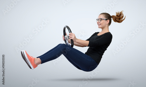 Young girl in glasses driver car with a wheel photo