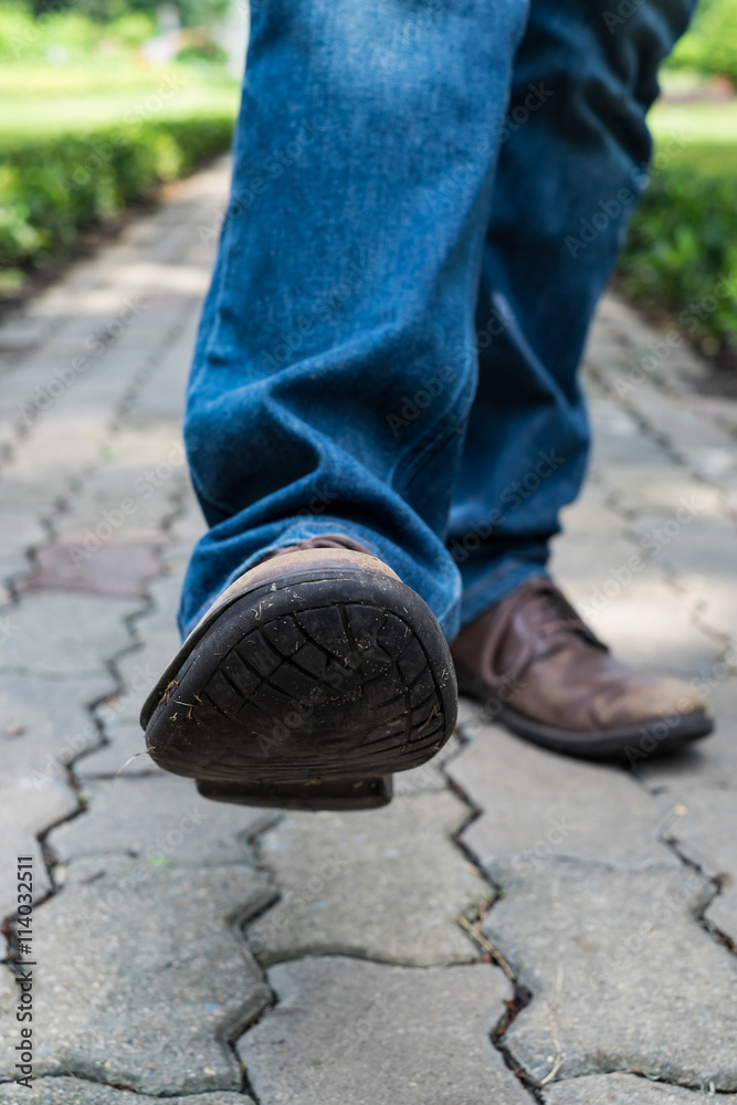 Man wearing jeans walking on the path to the park or garden Man wearing jeans walking on the path to the park or garden