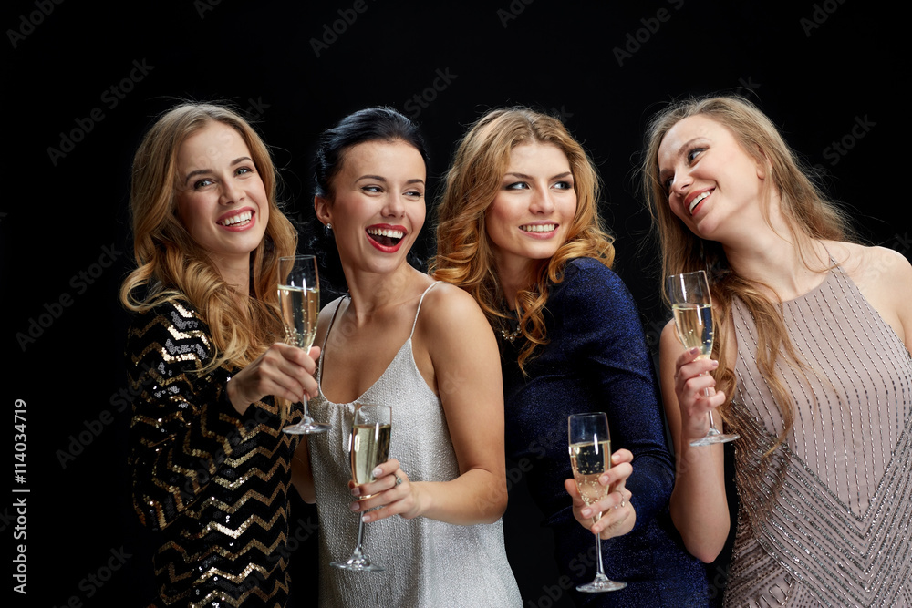 happy women with champagne glasses over black