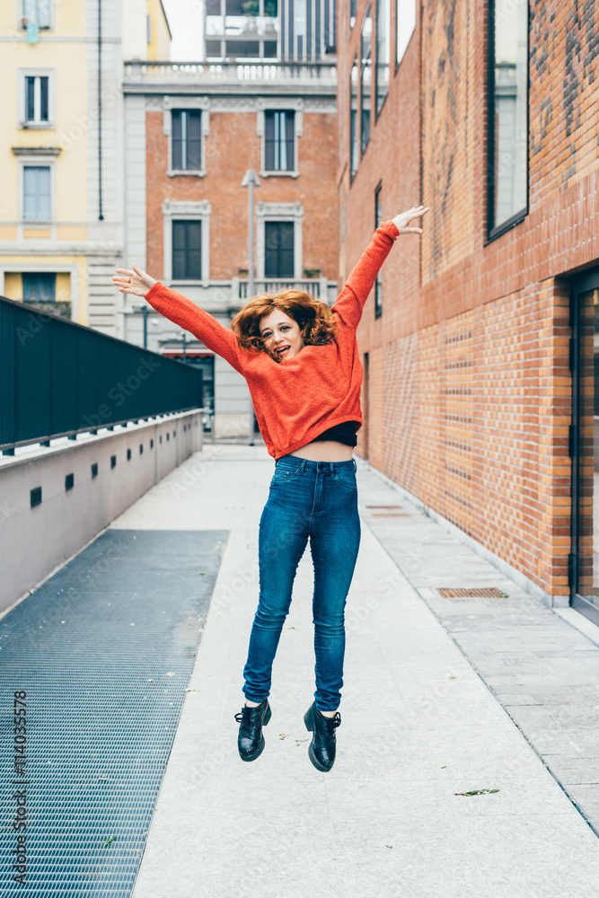 Young handsome redhead woman jumping outdoor in the city - girl power, satisfaction, goal concept Young handsome redhead woman jumping outdoor in the city - girl power, satisfaction, goal concept