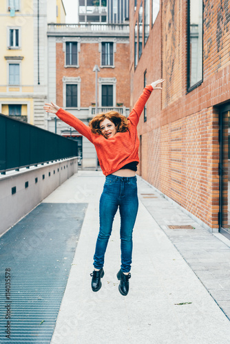 Young handsome redhead woman jumping outdoor in the city - girl power, satisfaction, goal concept © Eugenio Marongiu