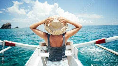 Happy woman with hat traveling on the boat in ocean