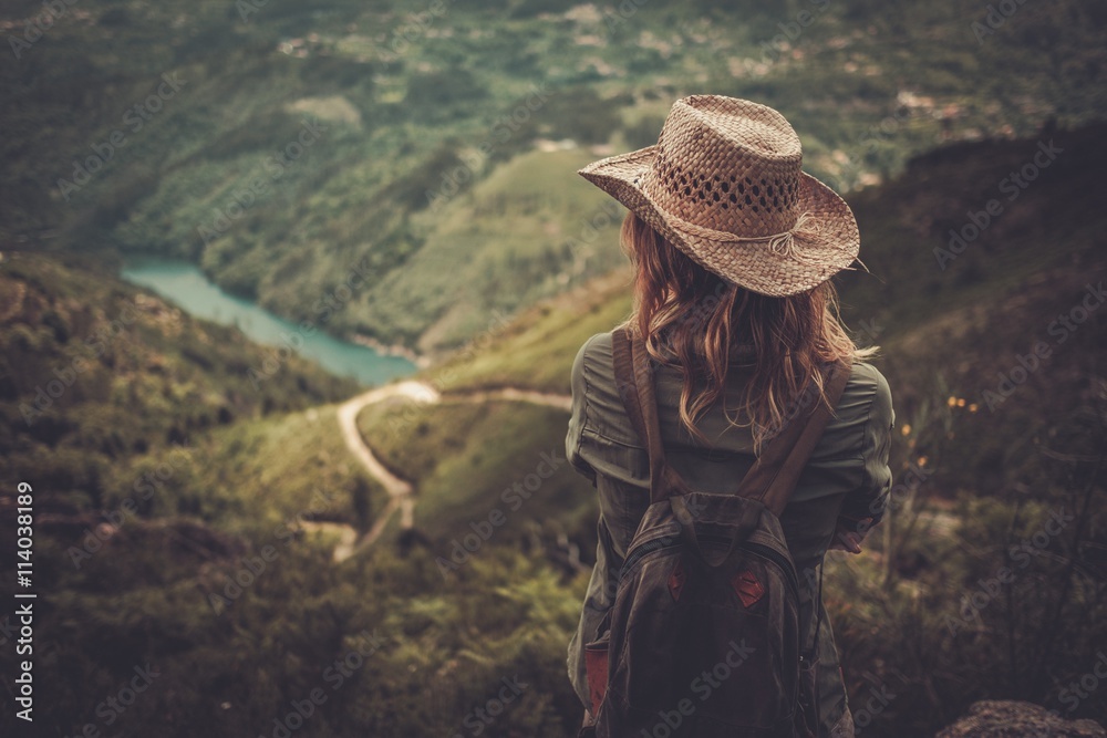 Woman hiker with backpack enjoying amazing valley landscapes on a top of mountain. - obrazy, fototapety, plakaty 