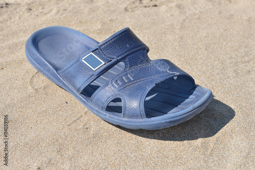 One blue dirty slipper for man on a sunny day on the beach. Vaca
