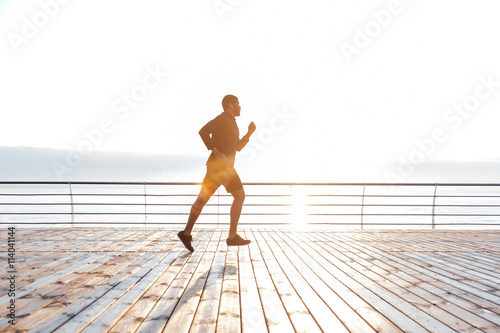 Sportsman running on pier at the sunset