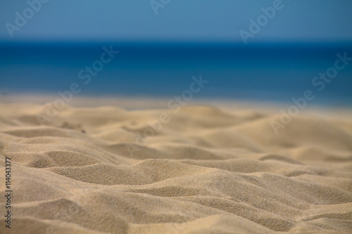 summer holidays - close up of sandy beach with ocean and blue sky in the back isolated