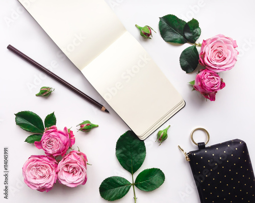 Colorful composition with sketchbook, roses and accessories. Flat lay, top view