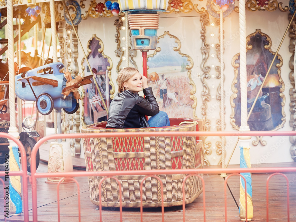 Young beautiful blond woman sitting on a Merry-Go-Round (carouse