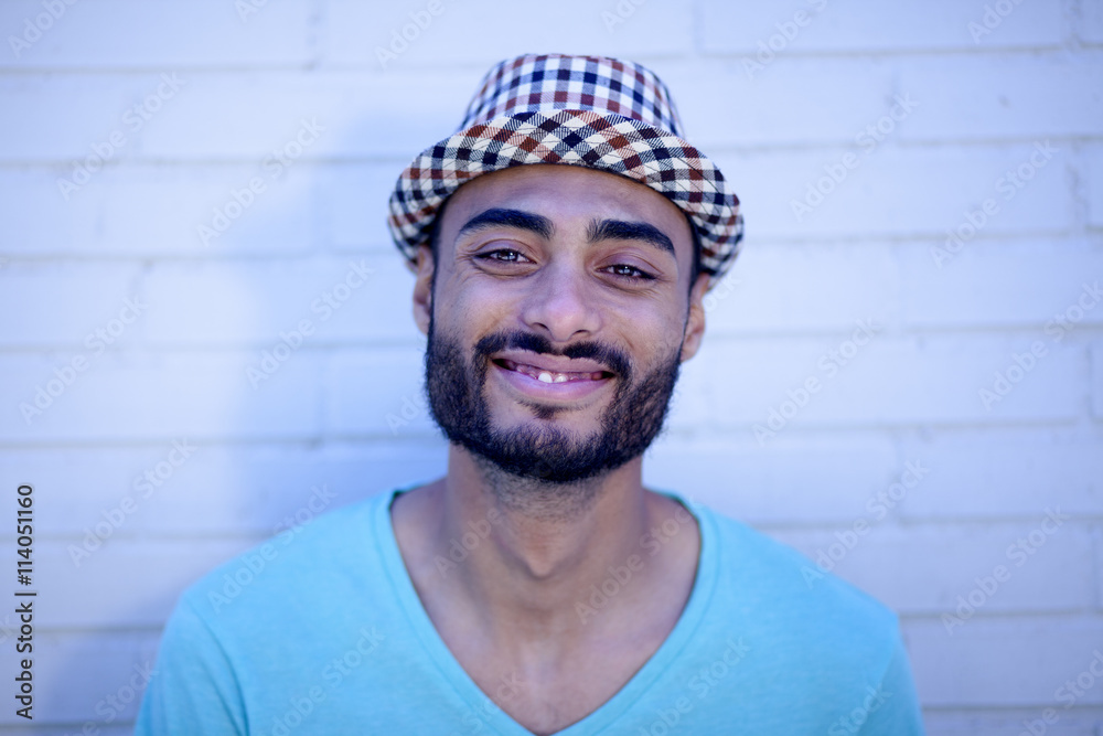 Retrato de joven mulato sonriendo sobre fondo de ladrillos blancos