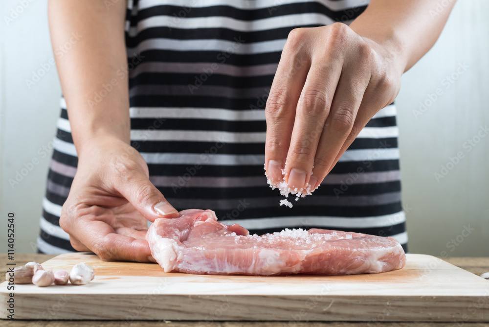 Food series : Closeup of woman's hands sprinkle salt on raw pork
