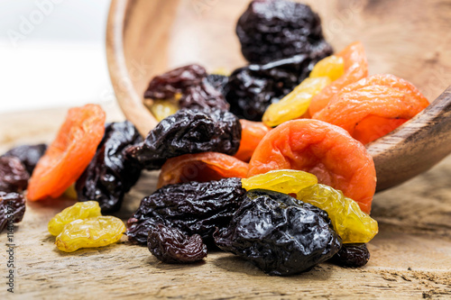 Mix of of dried fruits on a wooden background.