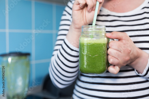 Healthy eating, food, diet, detox concept Female hands with green smoothie and tube