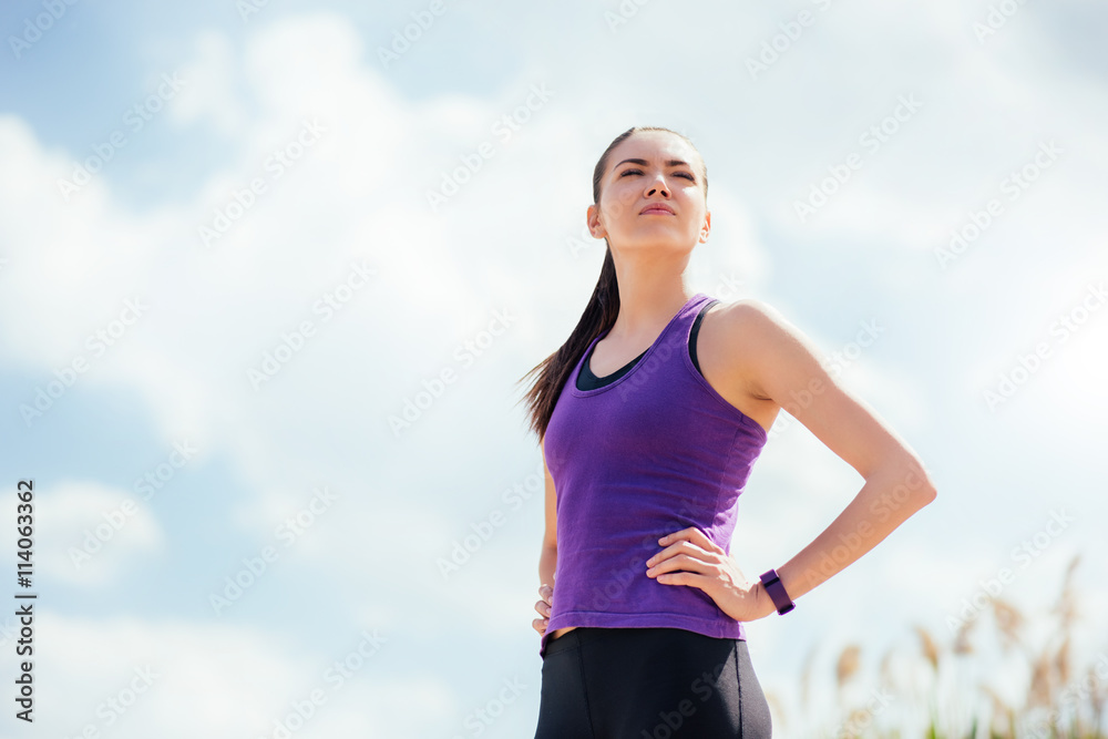 Standing sporty young beautiful woman before or after workout and running. Focused on exercises on sky background. Sport Standing sporty young beautiful woman before or after workout and running. Focused on exercises on sky background. Sport