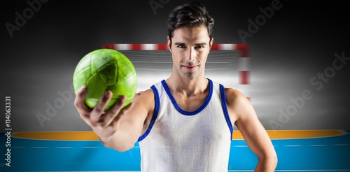 Composite image of portrait of happy male athlete holding a ball