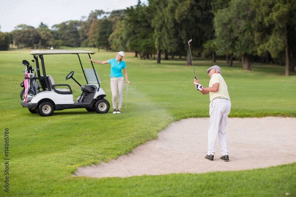 Obraz premium Mature golfer playing on sand trap by woman