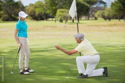 Mature man holding golf ball by woman 