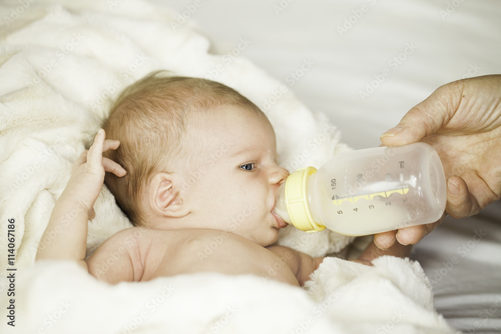 Baby drinking from bottle with nipple in mouth