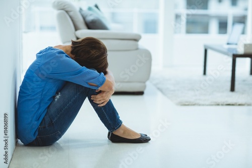 Sad woman sitting by wall