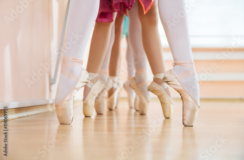 Legs of young ballerinas standing on pointe in row, ballet dancing class 