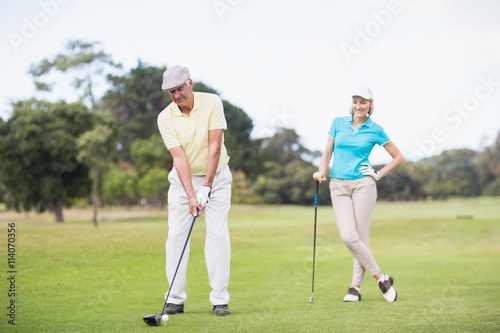Man playing golf while standing by woman