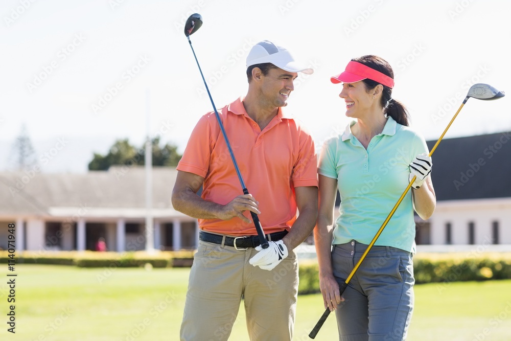 Happy couple holding golf clubs Happy couple holding golf clubs