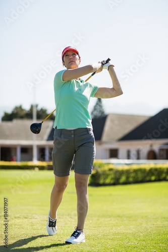 Full length of golfer woman taking shot 