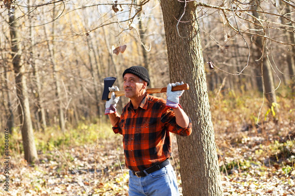 Portrait of senior lumberjack in nature holding an axe on his shoulder