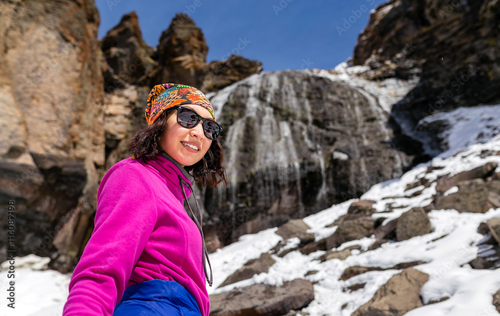 girl hiker enjoying mountain waterfall with snow at early spring girl hiker enjoying mountain waterfall with snow at early spring