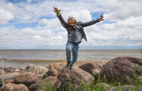 A young man jumping in rocks near Lake Peipus in Estonia,  the 5th largest Lake in Europe photo