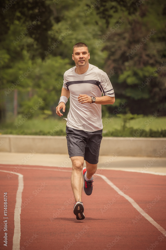 Morning training. Jogger running on the red running track. Workout, sport, healthy lifestyle concepts. Morning training. Jogger running on the red running track. Workout, sport, healthy lifestyle concepts.