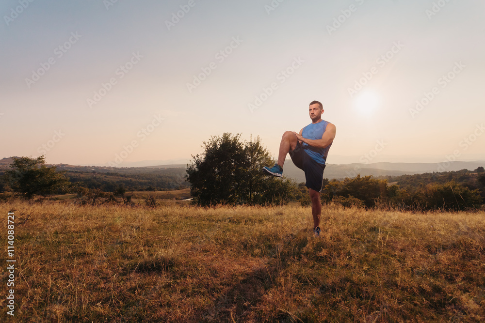 Athletic man in his 30s stretching his legs outdoor preparing for exercise