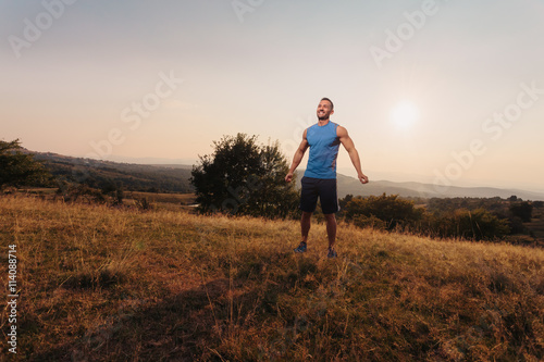 Attractive athletic man in his 30s outdoor smiling while taking a break in jogging