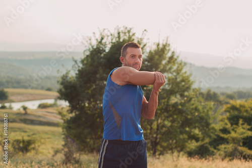 Attractive athletic man in his 30s stretching outdoor preparing for exercise
