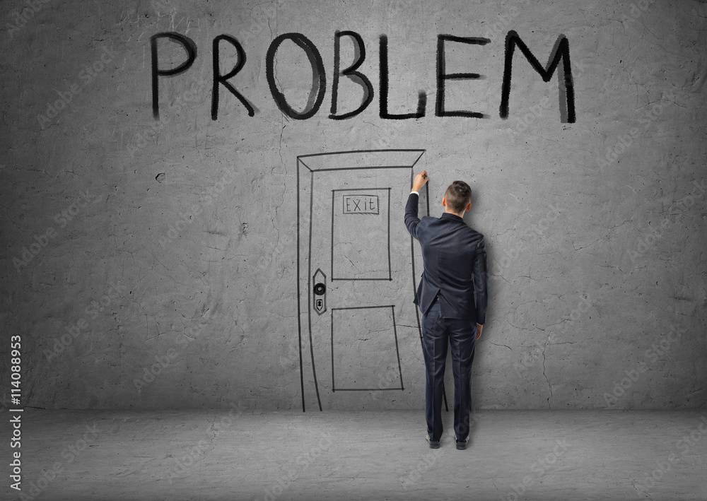 Businessman draws a door marked PROBLEM on the concrete wall. Businessman draws a door marked PROBLEM on the concrete wall.