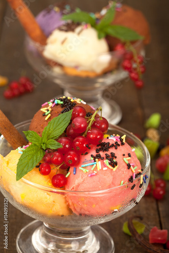 Ice cream dessert in two glass bowls with fresh currant, mint and chocolate crumbs, vertical