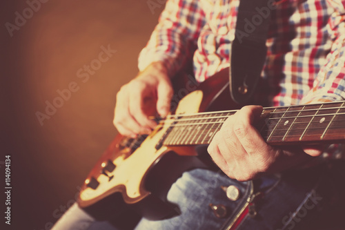 Young man playing on electric guitar