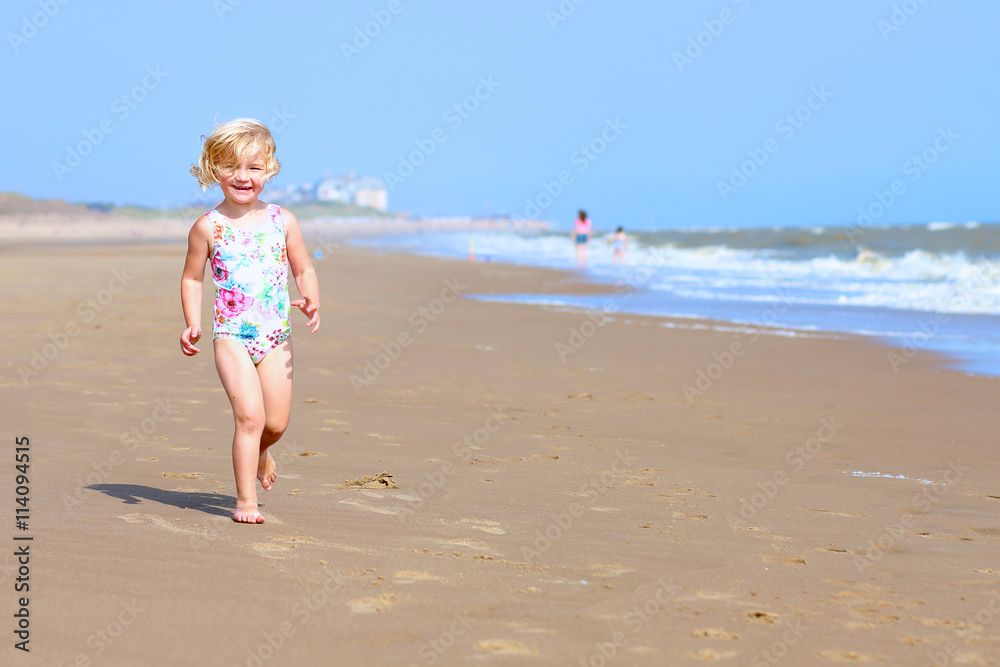 Cute active child playing on sandy beach. Happy little girl enjoying summer holidays on a sunny day. Family with young kids on vacation at the North Sea coast. Cute active child playing on sandy beach. Happy little girl enjoying summer holidays on a sunny day. Family with young kids on vacation at the North Sea coast.