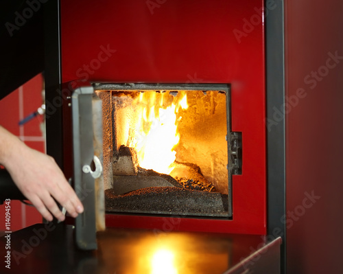 Human hand opening boiler door, closeup photo