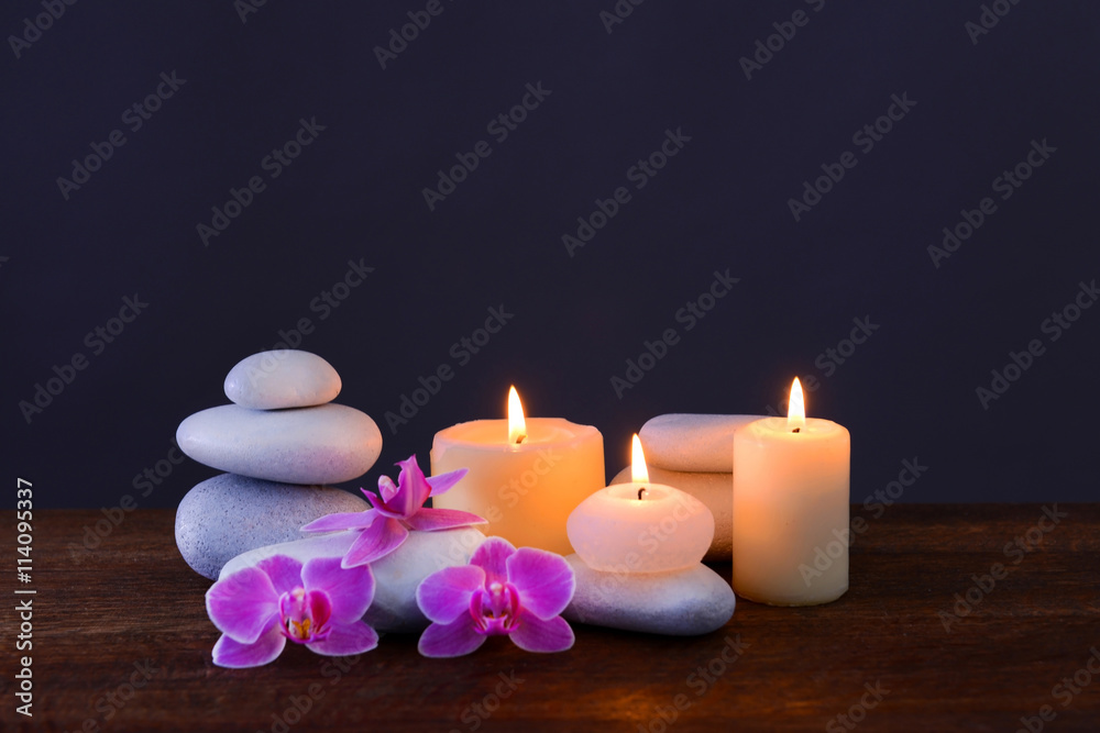 Spa stones with burning candles and flowers on grey background