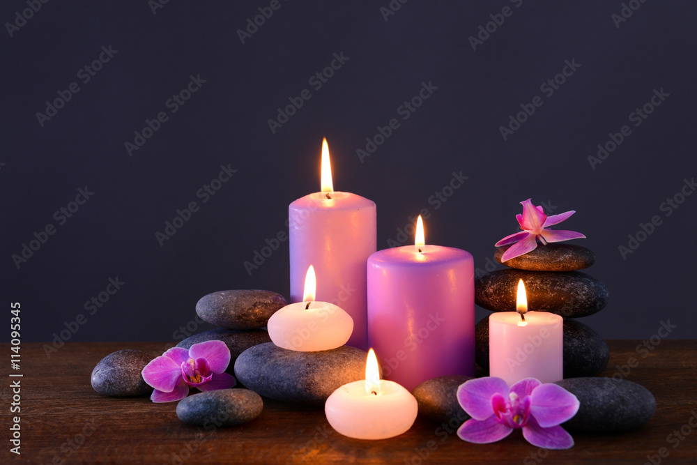 Spa stones with burning candles and flowers on grey background
