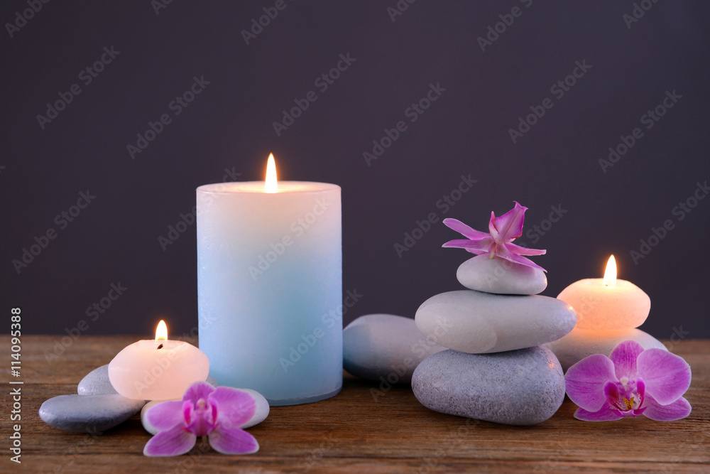 Spa stones with burning candle and flowers on grey background Spa stones with burning candle and flowers on grey background