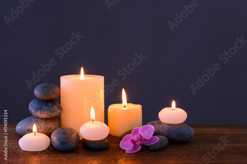 Spa stones with burning candles and flower on grey background
