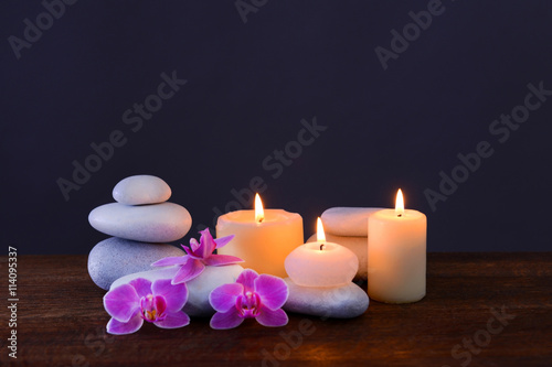 Spa stones with burning candles and flowers on grey background