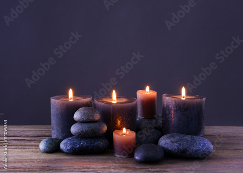 Spa stones with burning candles on grey background