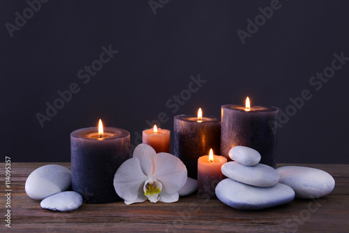 Spa stones with burning candles and flower on grey background