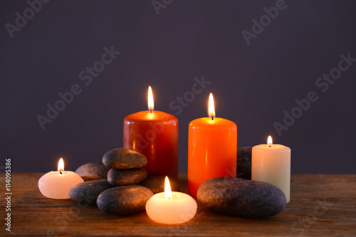 Spa stones with burning candles on grey background