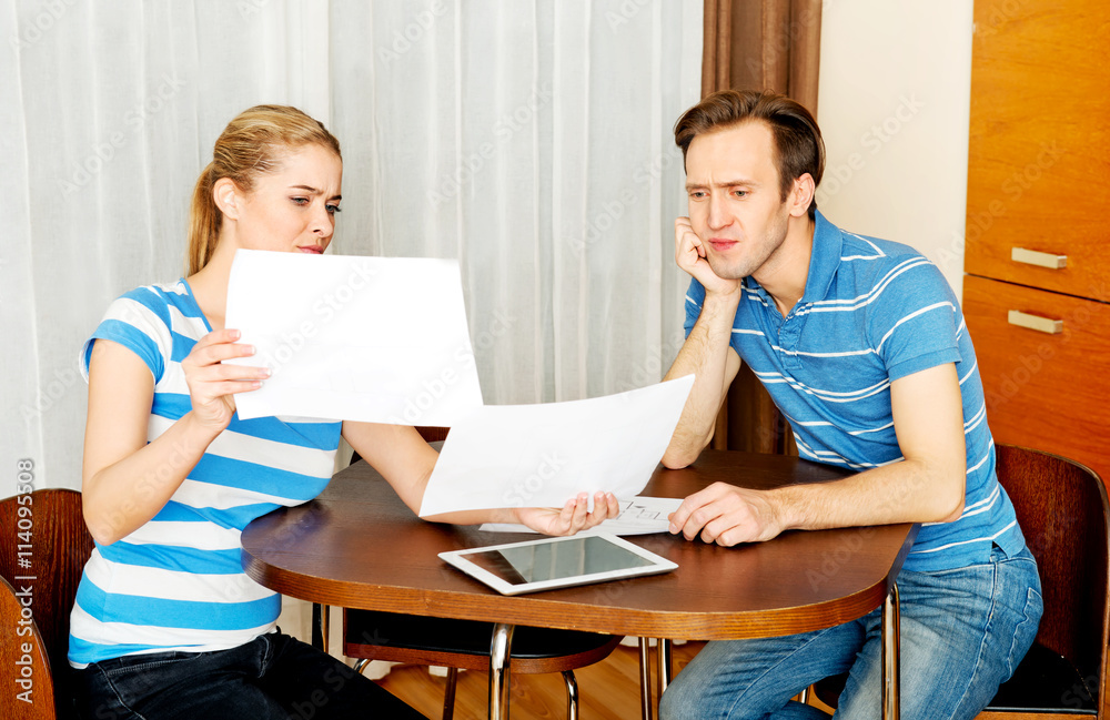 Young couple sitting at the desk and looking for plans of new house Young couple sitting at the desk and looking for plans of new house