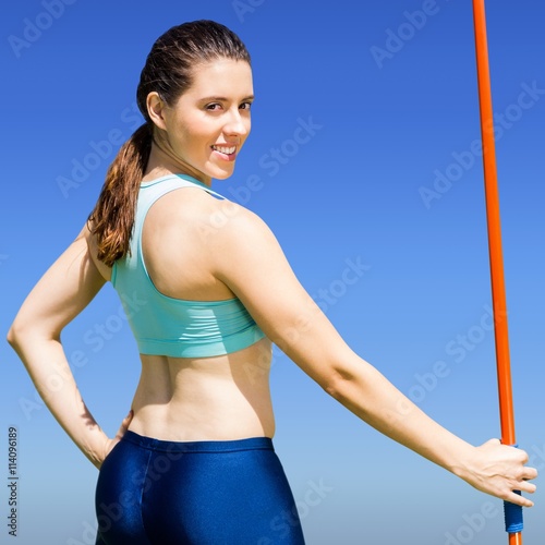 Composite image of rear view of sporty woman holding a javelin