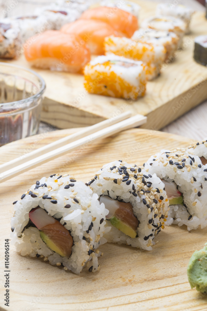 Different Sushi rolls,wasabi and ginger on a plate on wooden bac Different Sushi rolls,wasabi and ginger on a plate on wooden bac